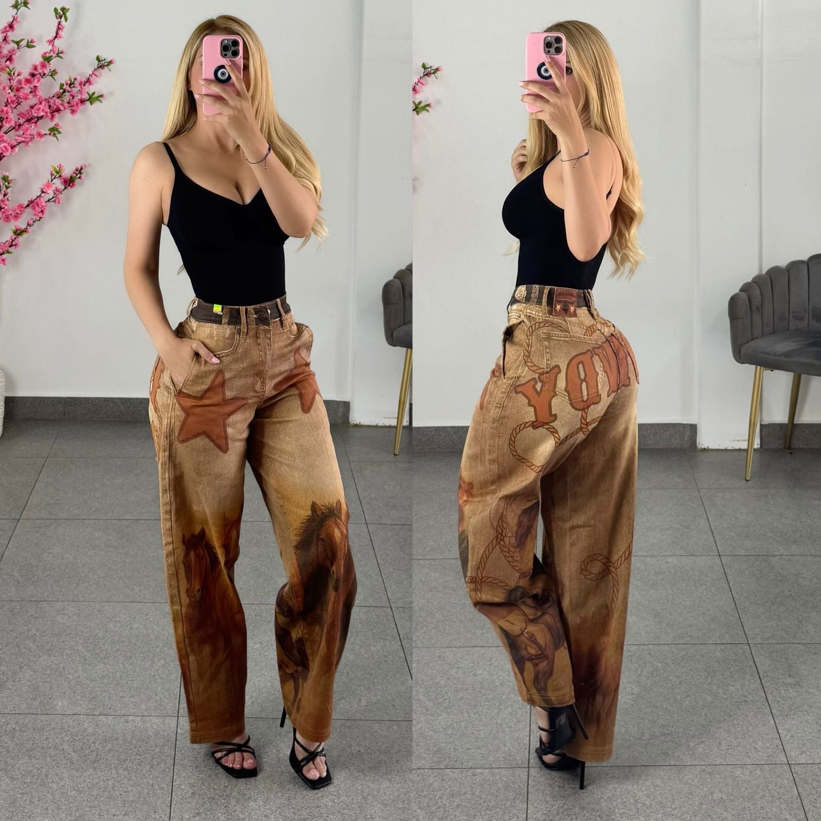 A woman modeling a pair of loose, wide-leg brown pants with a vintage western-style print, shown in a side-by-side front and back mirror selfie. She is wearing a black camisole top and black strappy heels.