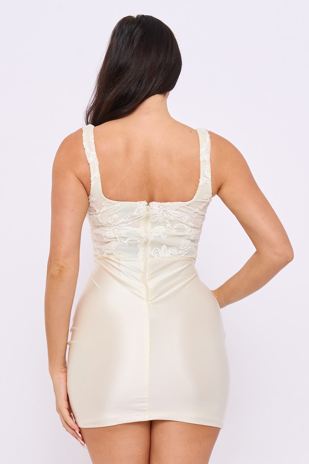 Woman wearing a beige dress with lace details on a white background