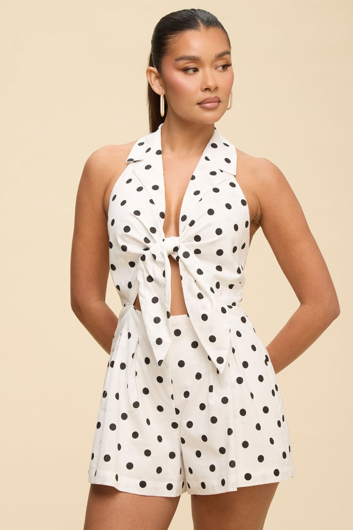 Woman wearing a white polka dot romper on a beige background