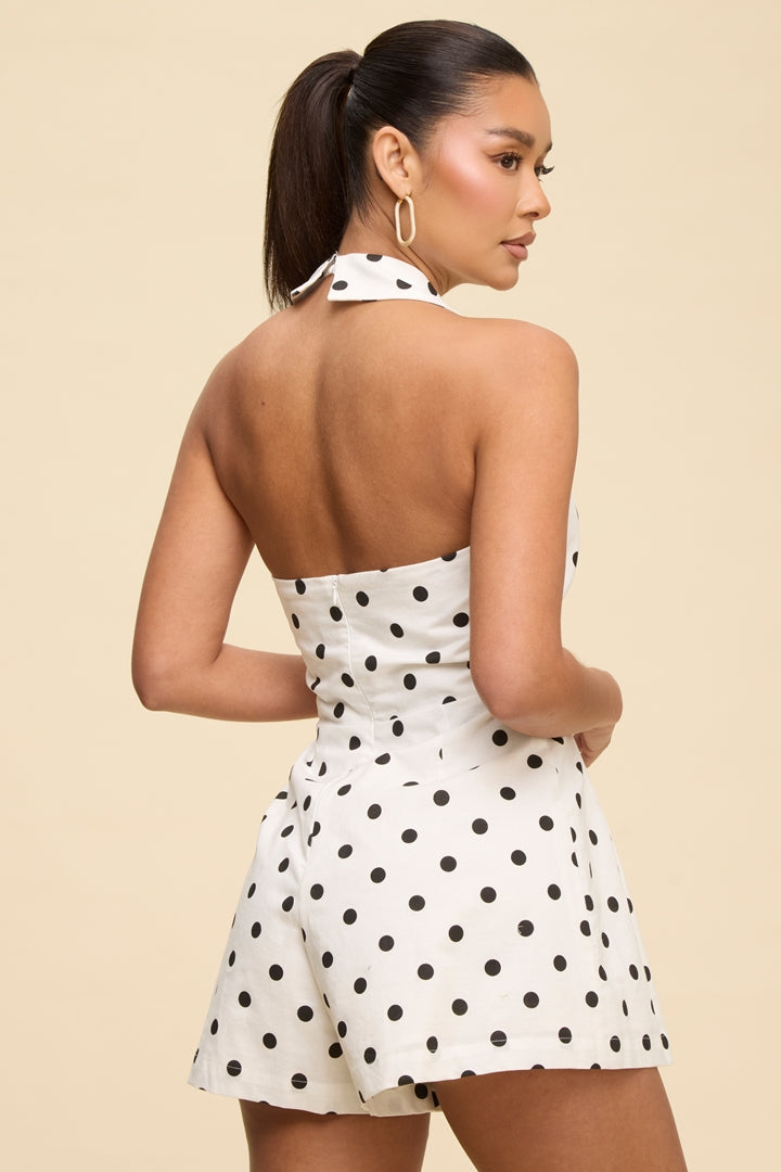 Woman wearing a white polka dot dress with a beige background