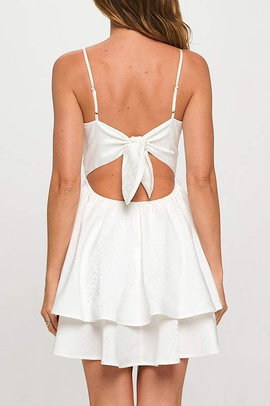 White dress with open back and bow detail on a white background
