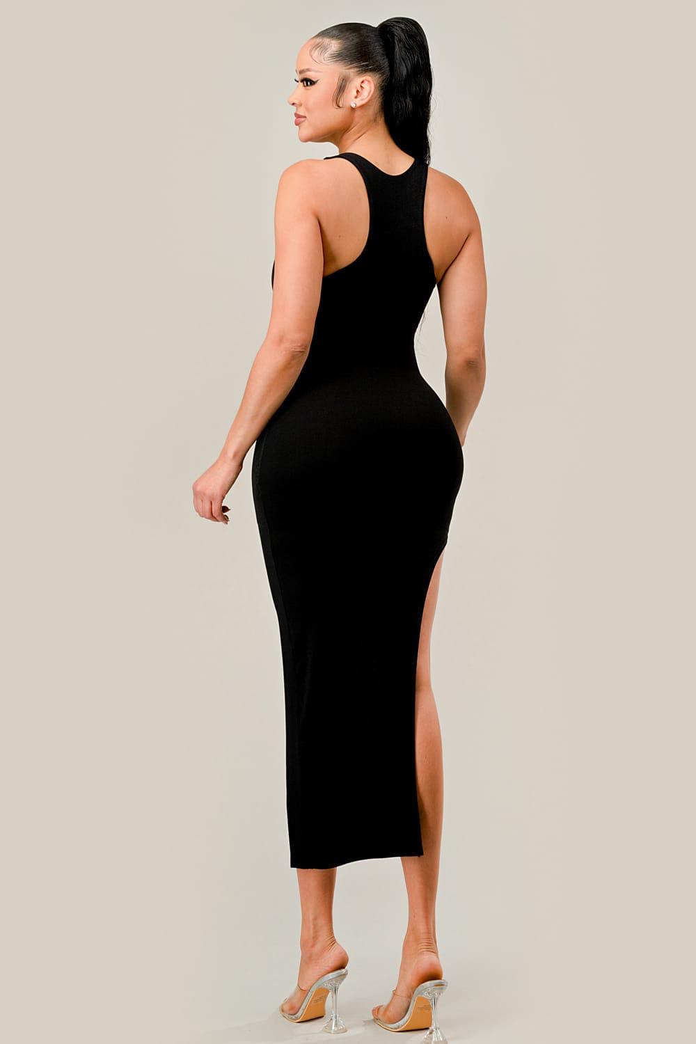 Woman wearing a black dress with a high slit on a plain background