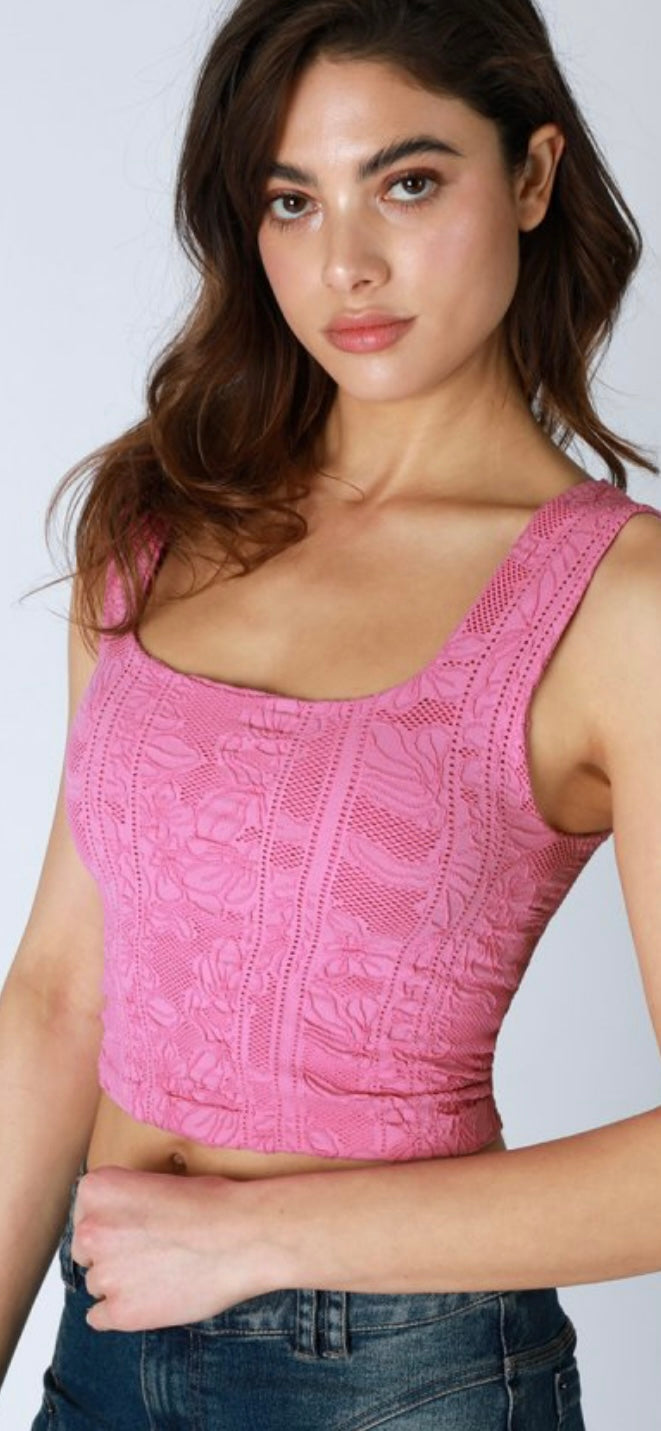 Woman wearing a pink textured tank top against a plain background