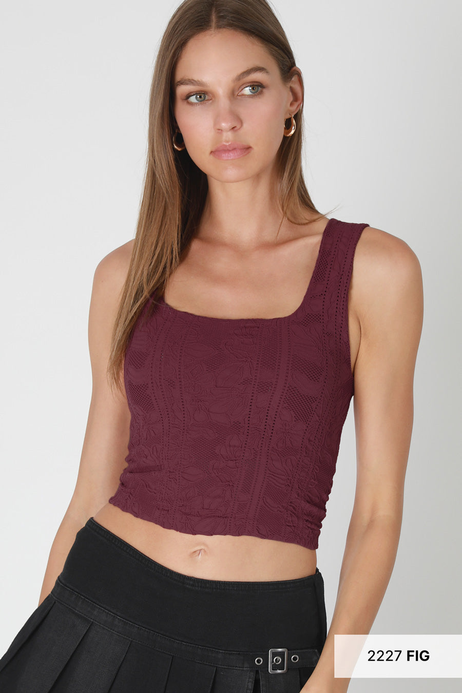 Woman wearing a burgundy tank top and black pleated skirt on a white background