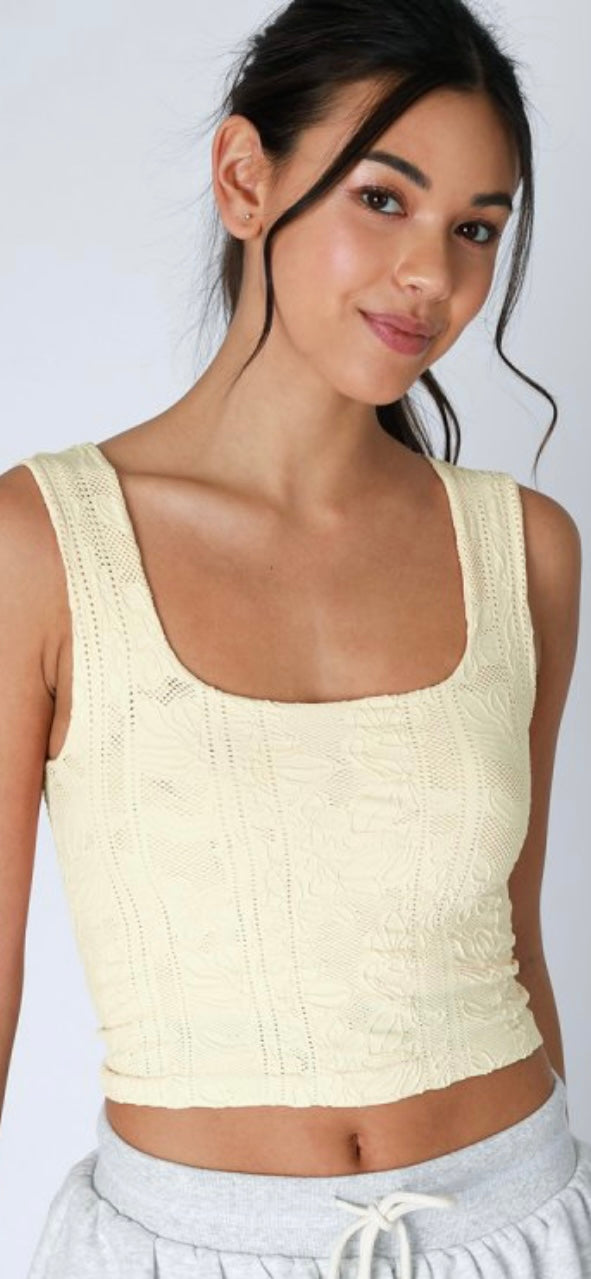 Woman wearing a light-colored tank top against a plain background
