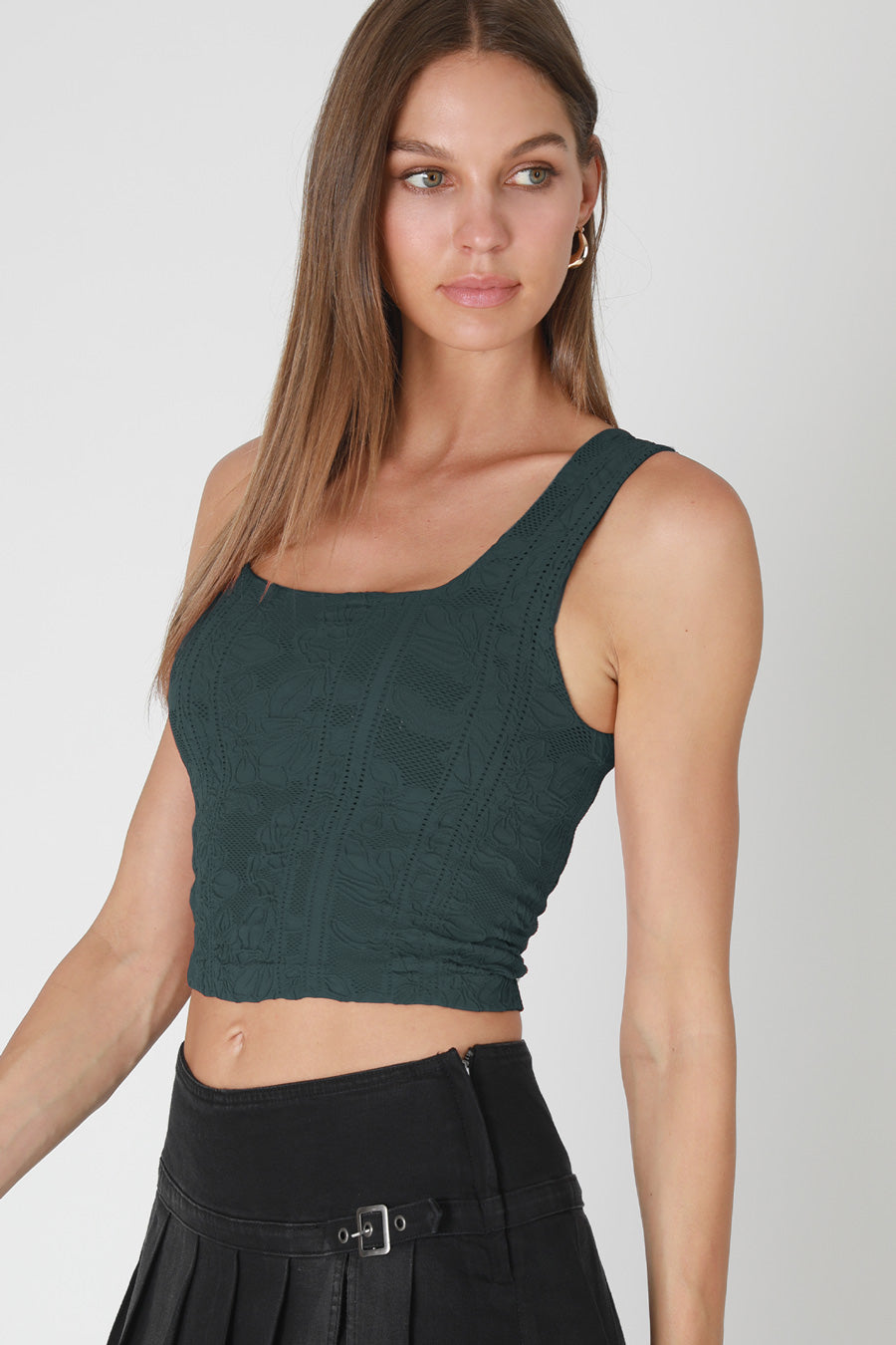 Woman wearing a green crop top and black skirt on a white background