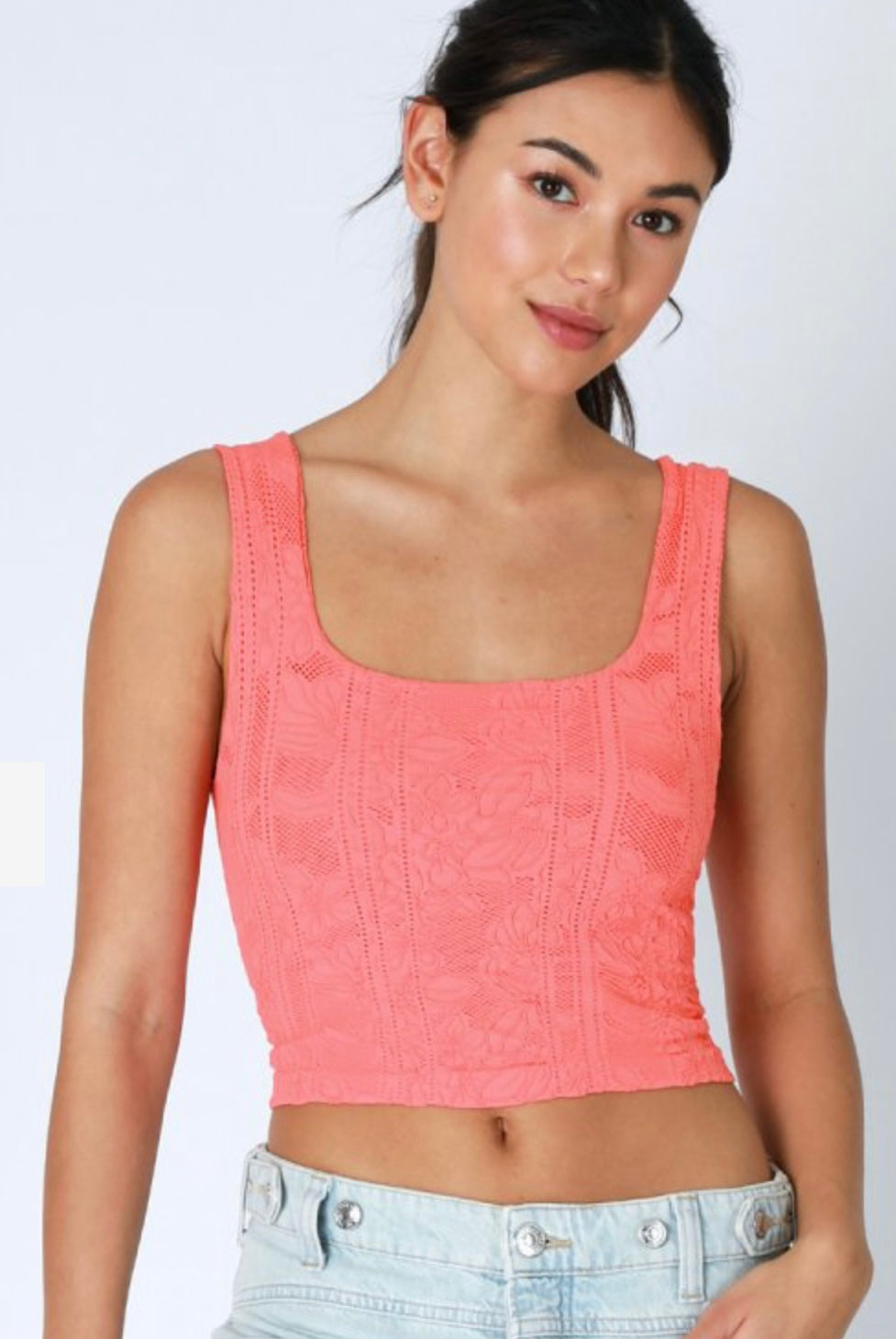 A woman wearing a pale lemon color lace crop top.