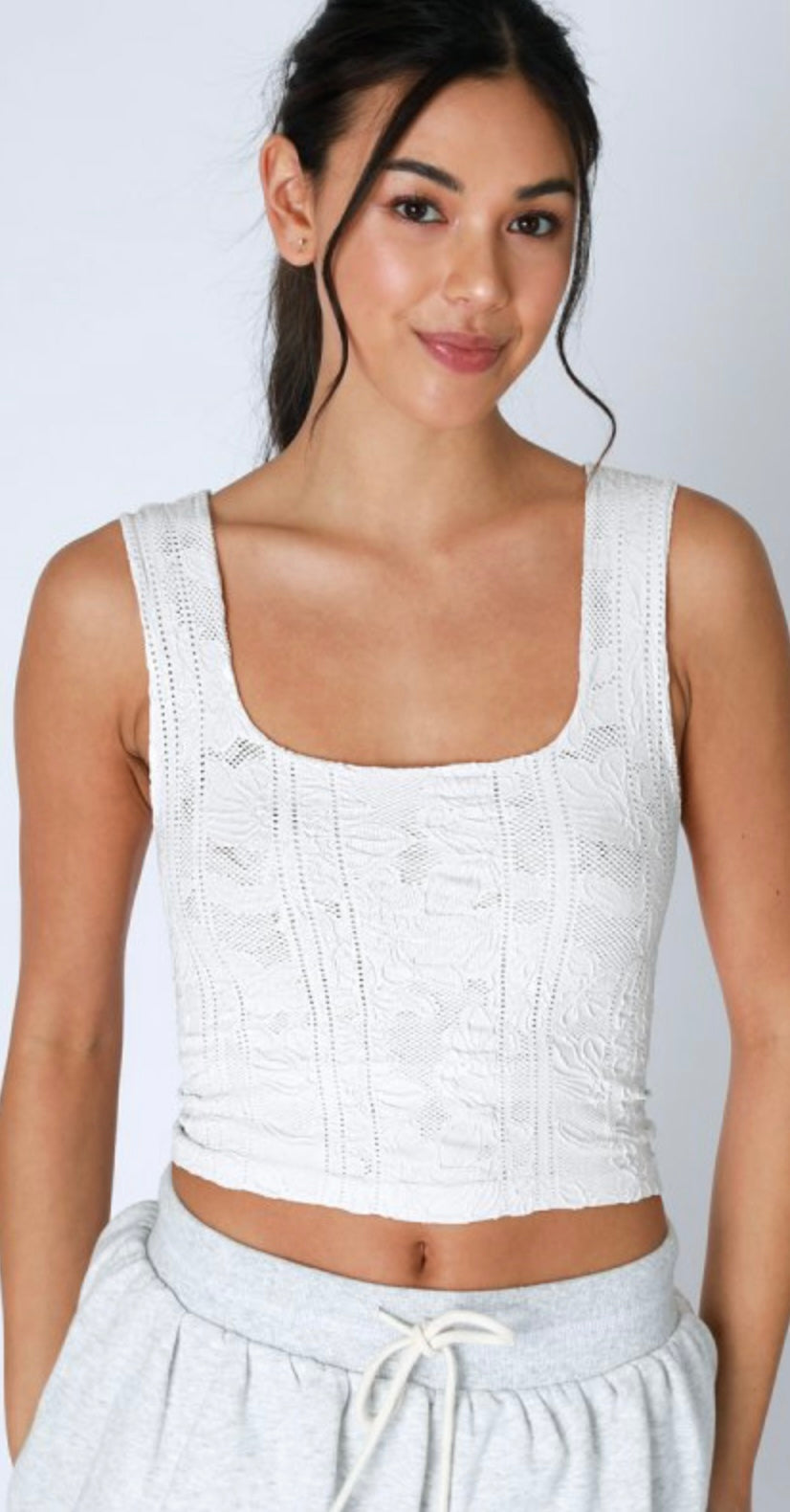 A woman wearing a pale lemon color lace crop top.
