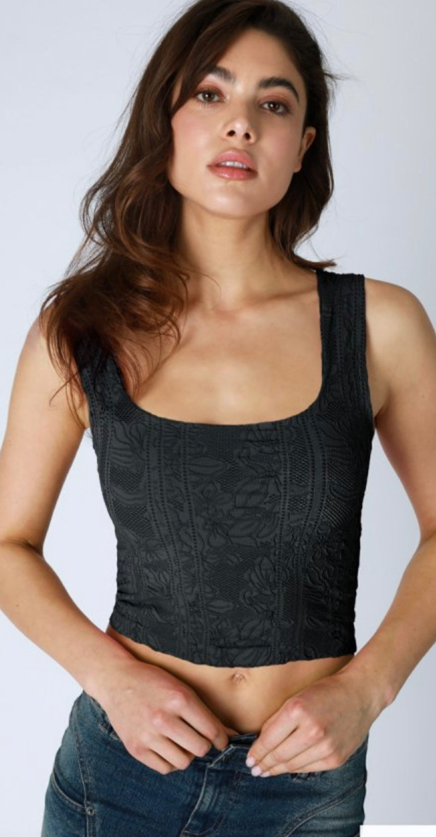 A woman wearing a pale lemon color lace crop top.