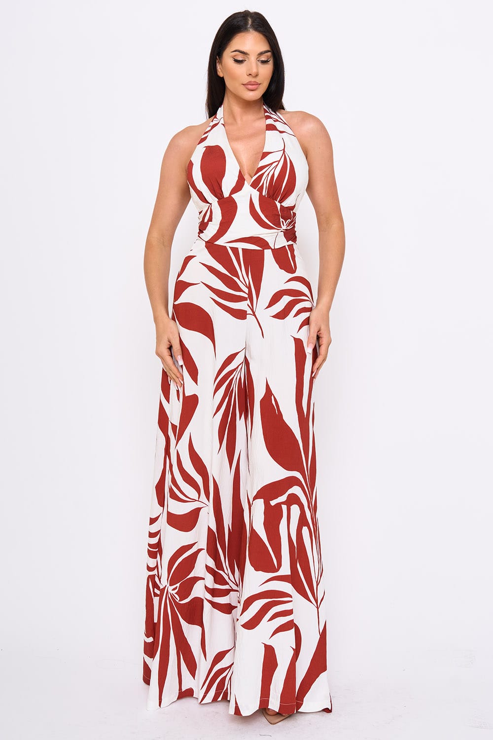 Woman wearing a red and white patterned halter neck jumpsuiton a white background