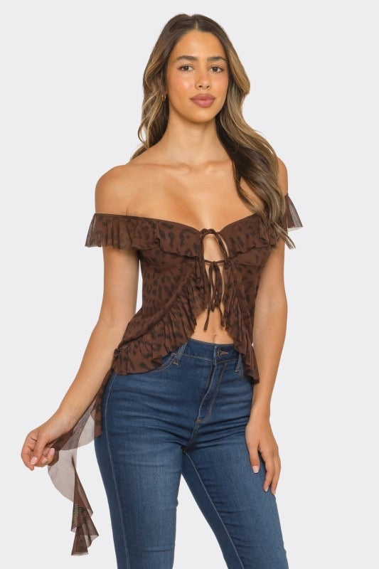 Woman wearing a brown off-shoulder top with ruffled sleeves and blue jeans on a white background