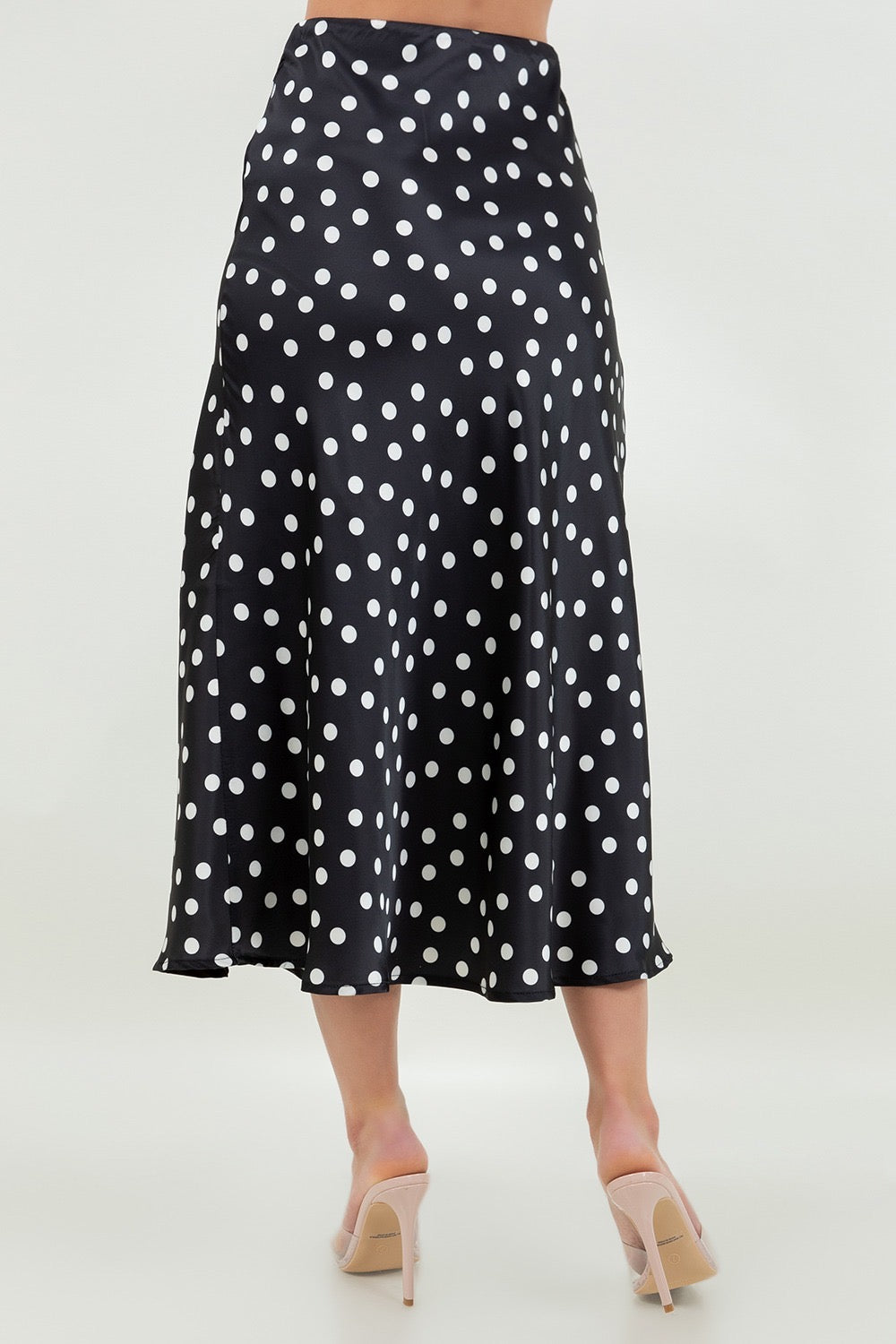 Black polka dot skirt worn by a person on a white background