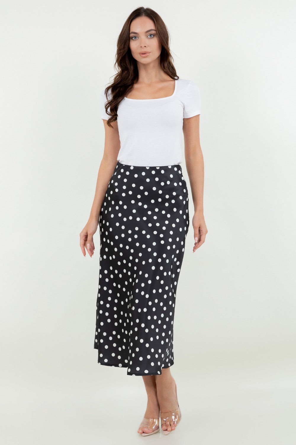 Woman wearing a white top and black polka dot skirt on a white background