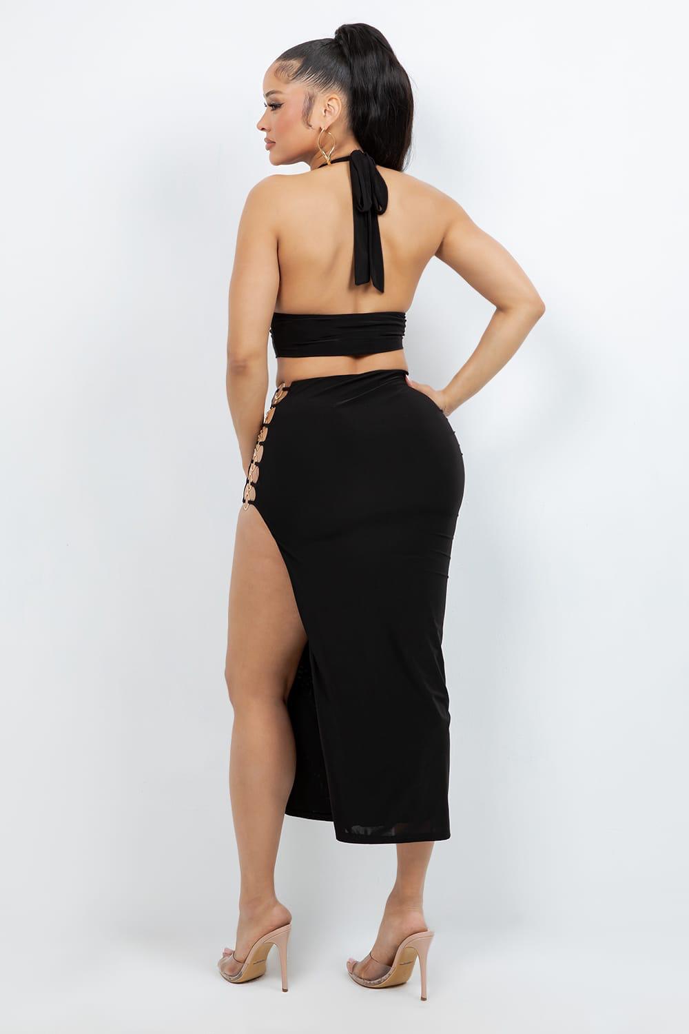 Woman wearing a black halter top and skirt with a high slit on a white background