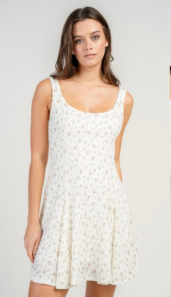 Woman wearing a white floral dress against a plain background